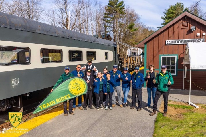 Group of people posing with a train near Hadley/Luzerne station.