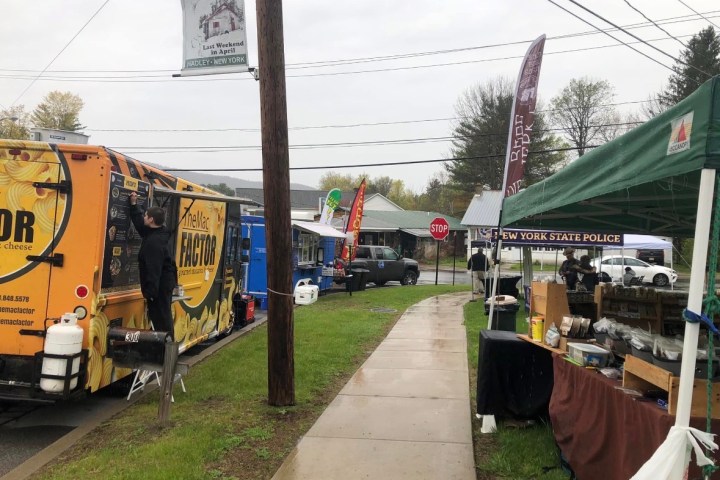 Food trucks and stalls at outdoor event on a cloudy day, featuring 'The Mac Factor' truck.