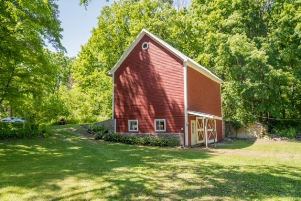 a large brick building with a clock on top of a lush green field