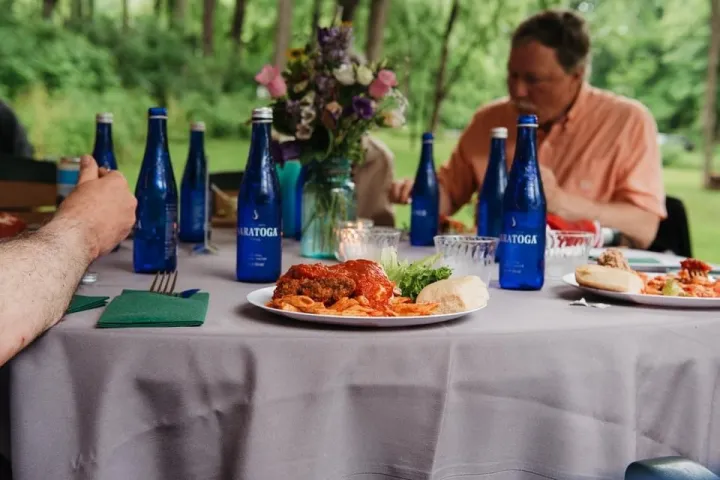 a person sitting at a table with food and a bottle of wine