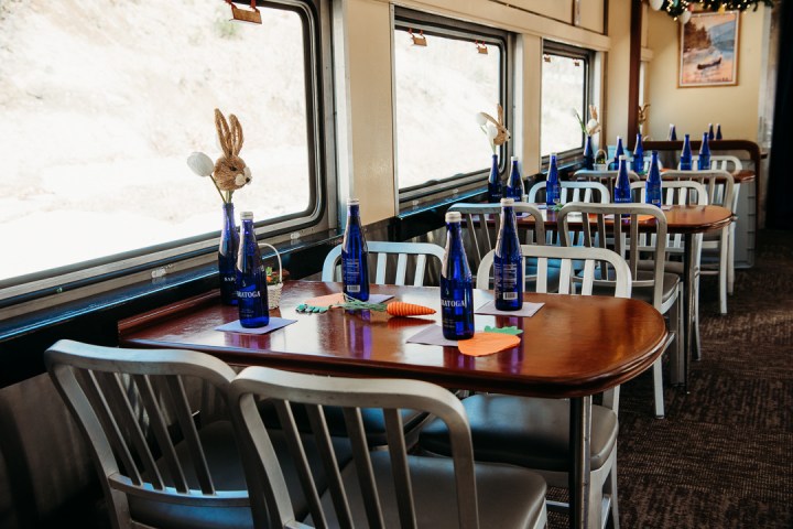 A dining car with tables set with blue bottles and bunny decorations.