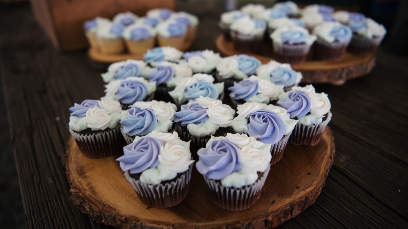 Cupcakes with purple and white frosting on wooden platters.