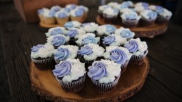 Cupcakes with purple and white frosting on wooden platters.