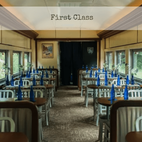 Empty train dining car with blue bottles on tables.